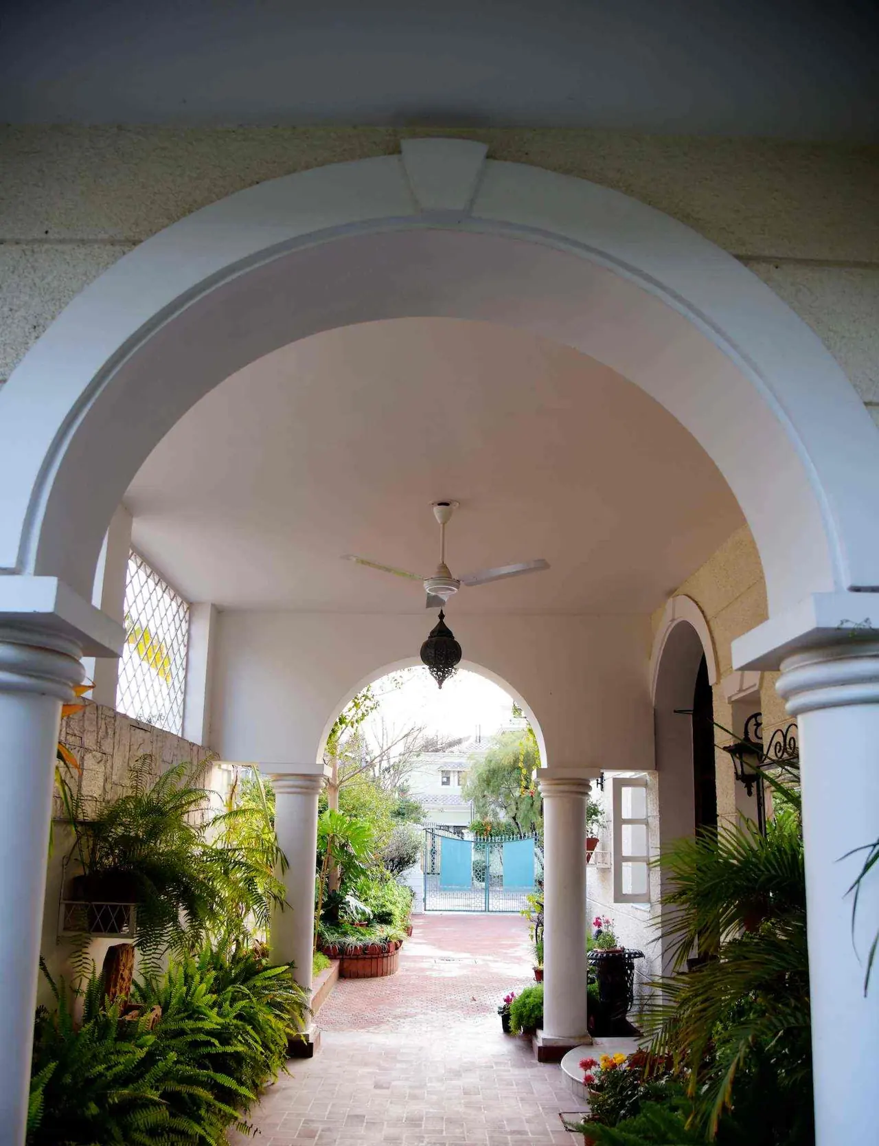 Arcadia, a residence in Wave Estate, Mohali: view through white arches along a shaded, plant-lined walkway