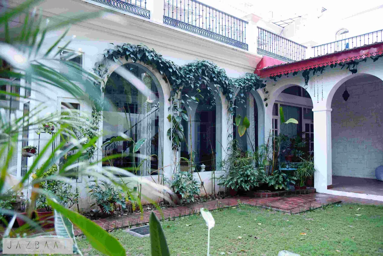 Arcadia, a residence in Wave Estate, Mohali: white arched verandas with climbing plants around a lawn courtyard