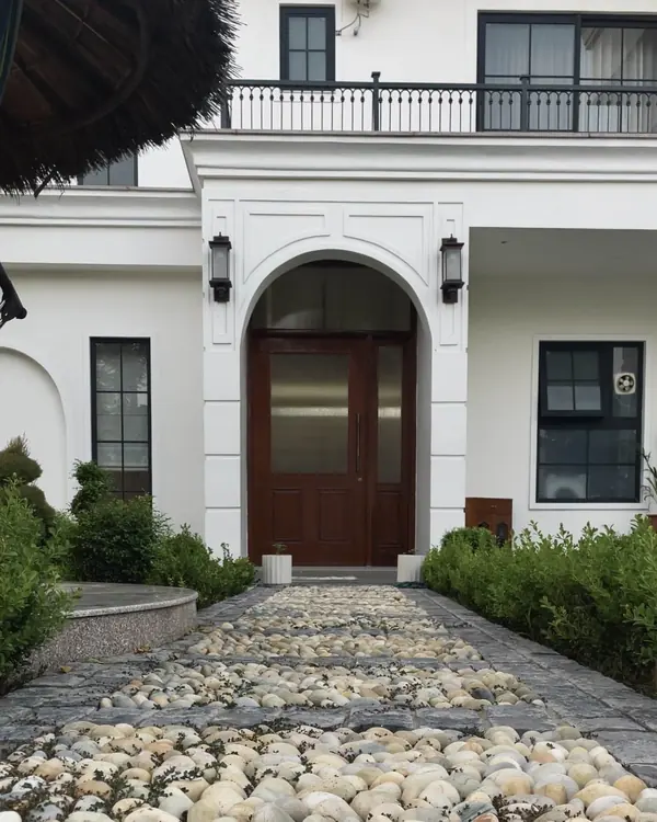 Saidpur Residence: arched timber entrance door reached by a pebble-lined path