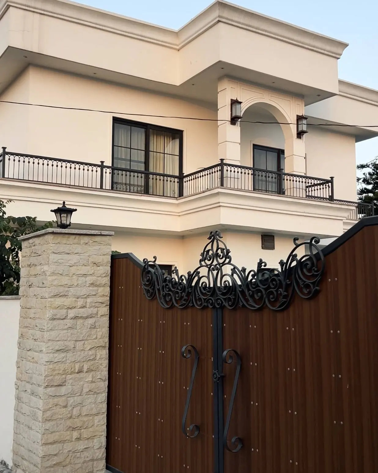 Saidpur Residence: white two-storey facade with a balcony, behind a carved timber gate and sandstone pillar